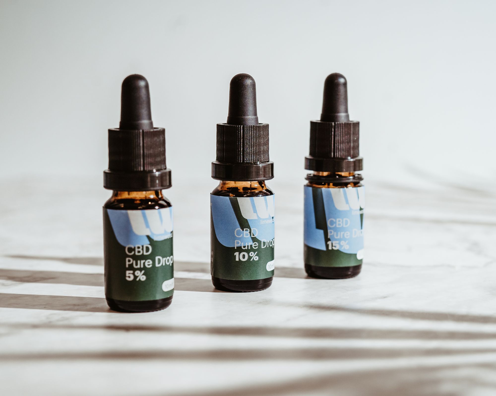 CBD Pure Drop drei kleine braune Flaschen auf Marmor