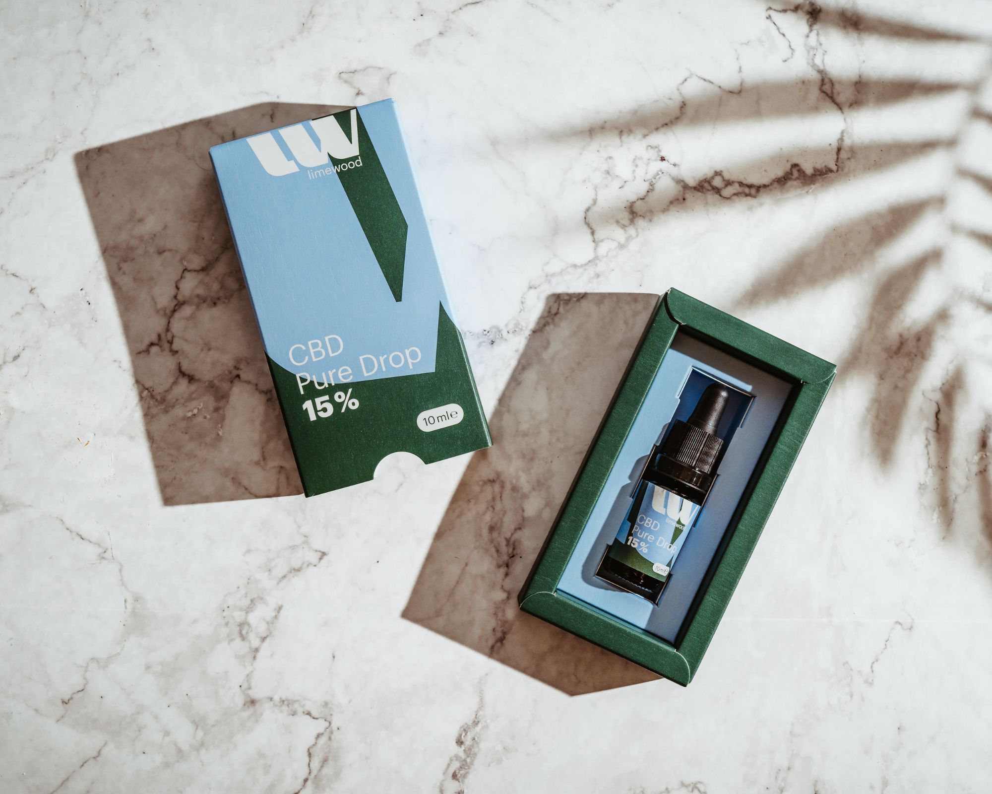 CBD Pure Drop kleine braune Flasche in der Verpackung auf Marmor