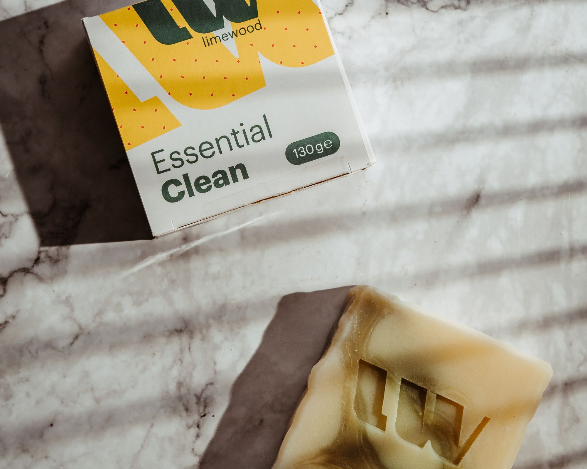 Eine Essential Clean Seife liegt neben der gelben Schachtel